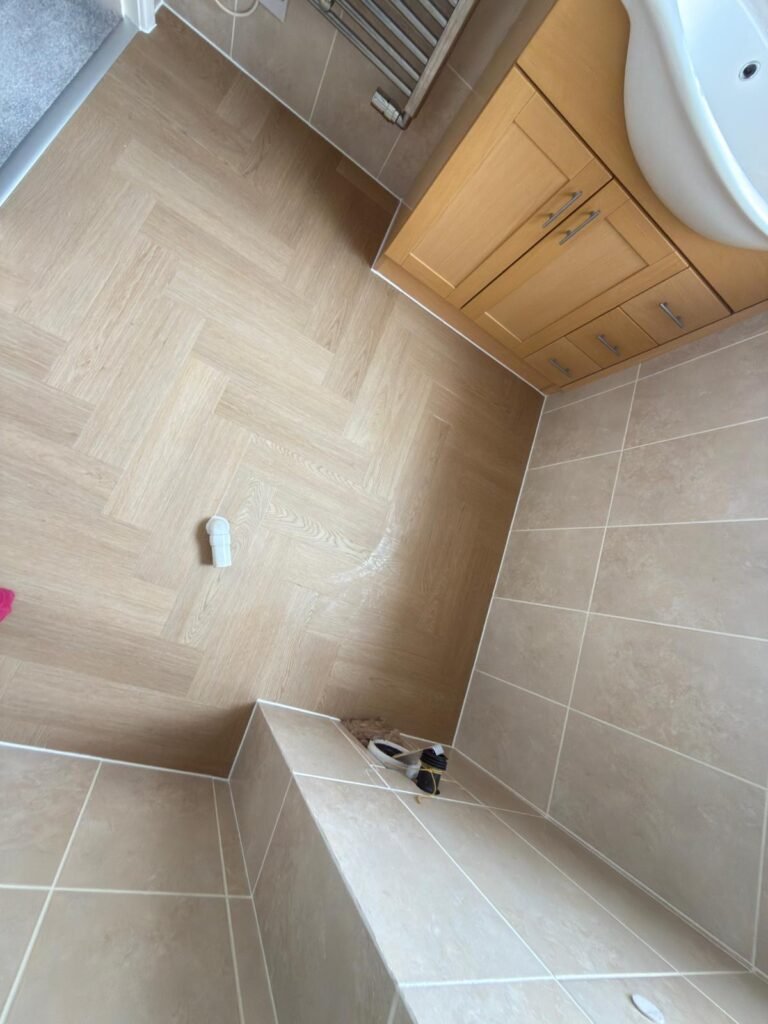 Light oak herringbone LVT fitted in a bathroom around the vanity unit