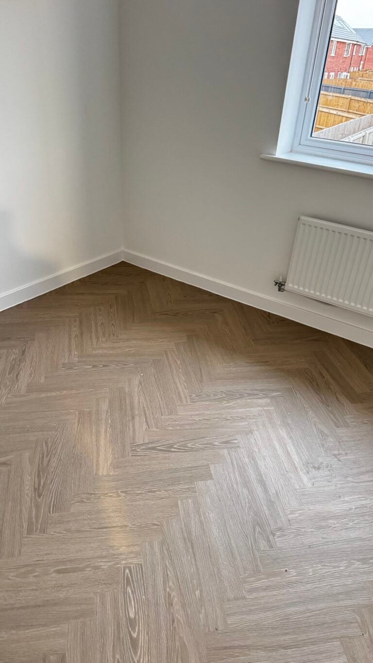 Light grey-oak herringbone LVT fitted in a bedroom