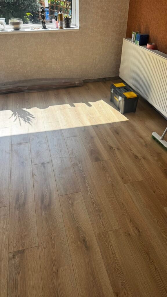 Warm natural oak laminate fitted in a sunlit lounge by Prime Carpets & Flooring